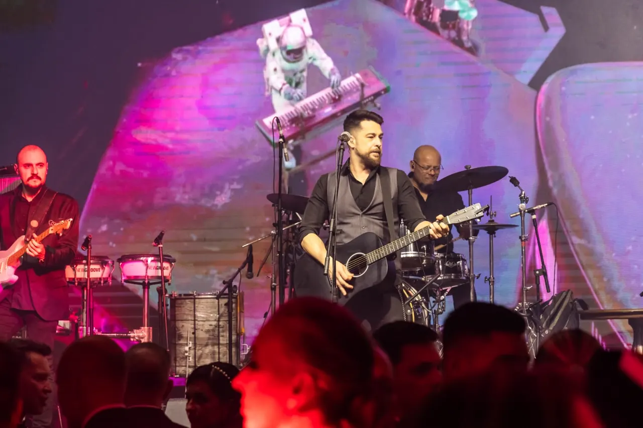 Dani Vendramini com a banda num palco com telão